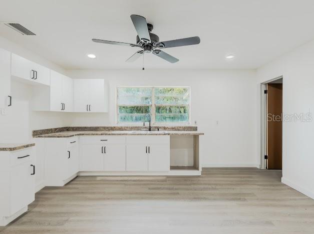 A kitchen with white cabinets, light wood-look flooring, a ceiling fan, and a window — 1440 SE 1ST TERRACE, GAINESVILLE, FL