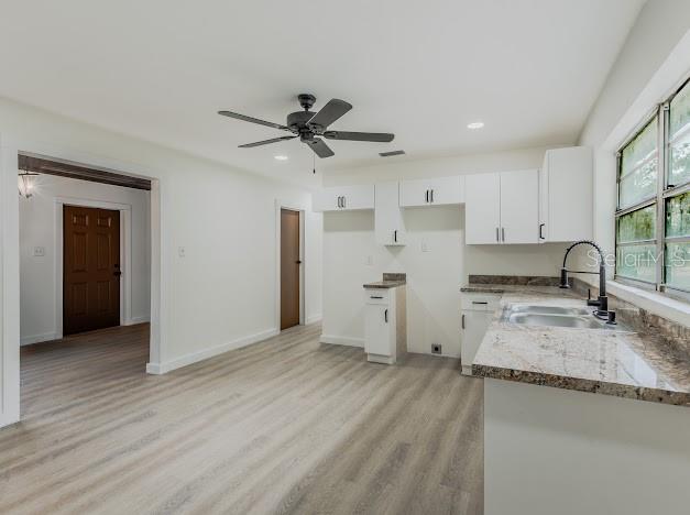 A kitchen with white cabinets, granite countertops, and light wood-look flooring — 1440 SE 1ST TERRACE, GAINESVILLE, FL