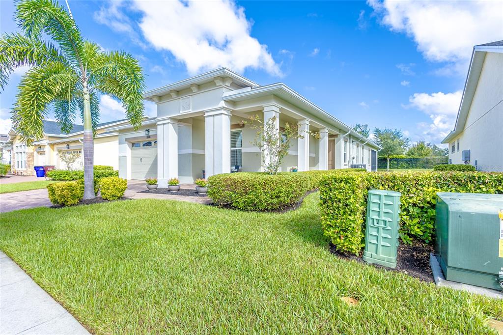 A single-story house with a columned porch, manicured hedges, and a palm tree in front — 2606 MEADOWEDGE LOOP, ST CLOUD, FL