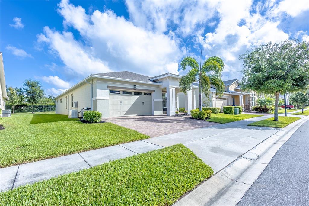 A single-story house with a beige exterior, a two-car garage, and a palm tree — 2606 MEADOWEDGE LOOP, ST CLOUD, FL