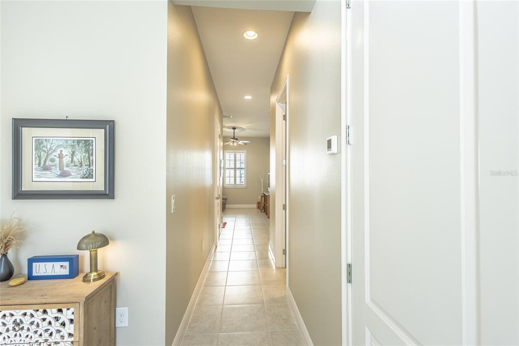 A hallway with tile flooring leads from a foreground room toward a windowed space — 2606 MEADOWEDGE LOOP, ST CLOUD, FL