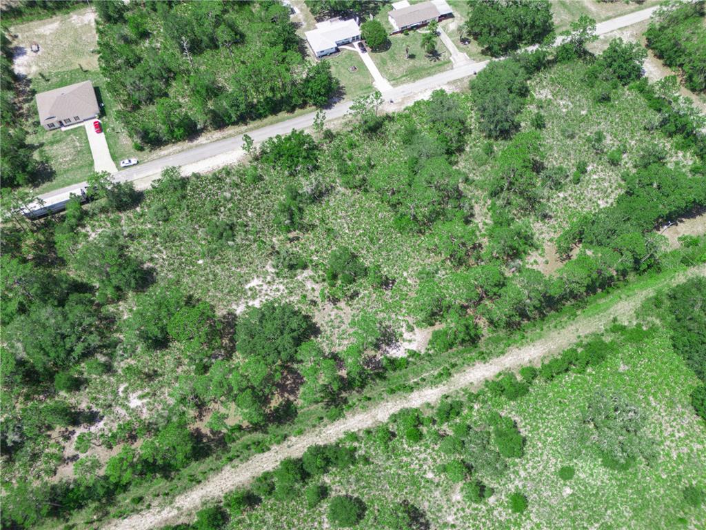 An aerial view shows a vacant, wooded residential lot adjacent to a paved road — 618 GARDENIA DRIVE, INDIAN LAKE ESTATES, FL