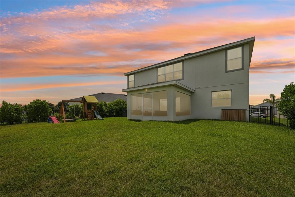 The exterior of a two-story house with a screened-in porch and a backyard playground — 16113 67TH COURT E, PARRISH, FL