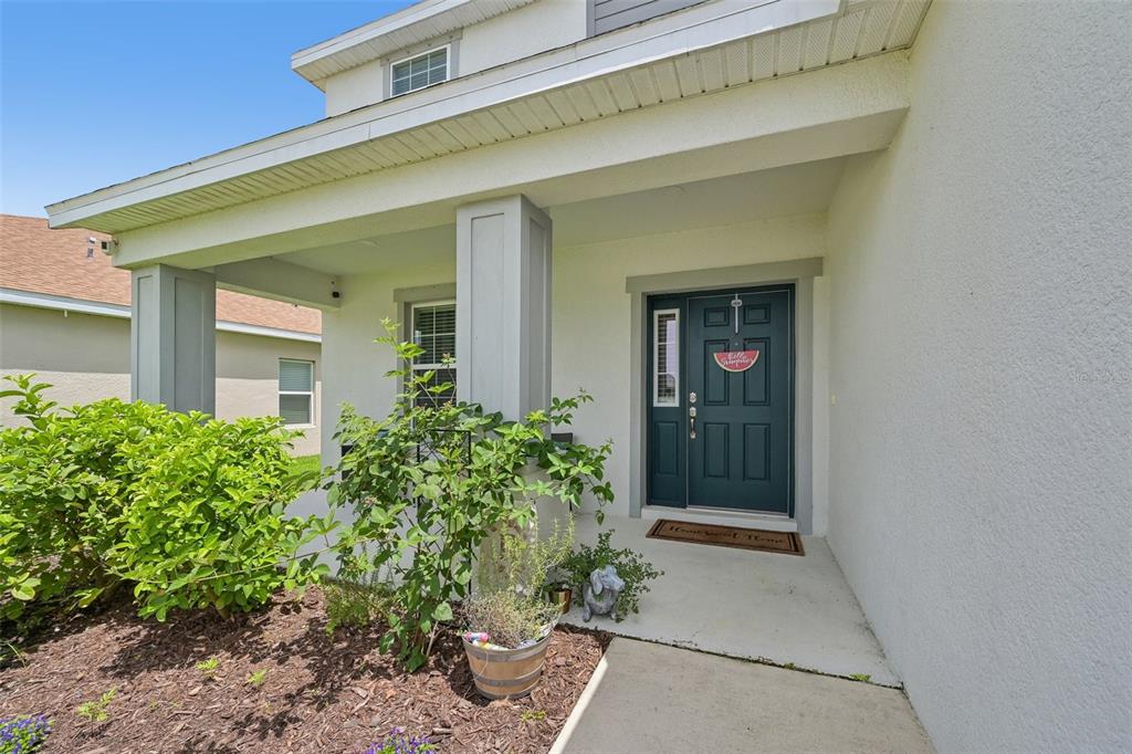 A covered front porch leads to a dark blue front door with a side window — 16113 67TH COURT E, PARRISH, FL
