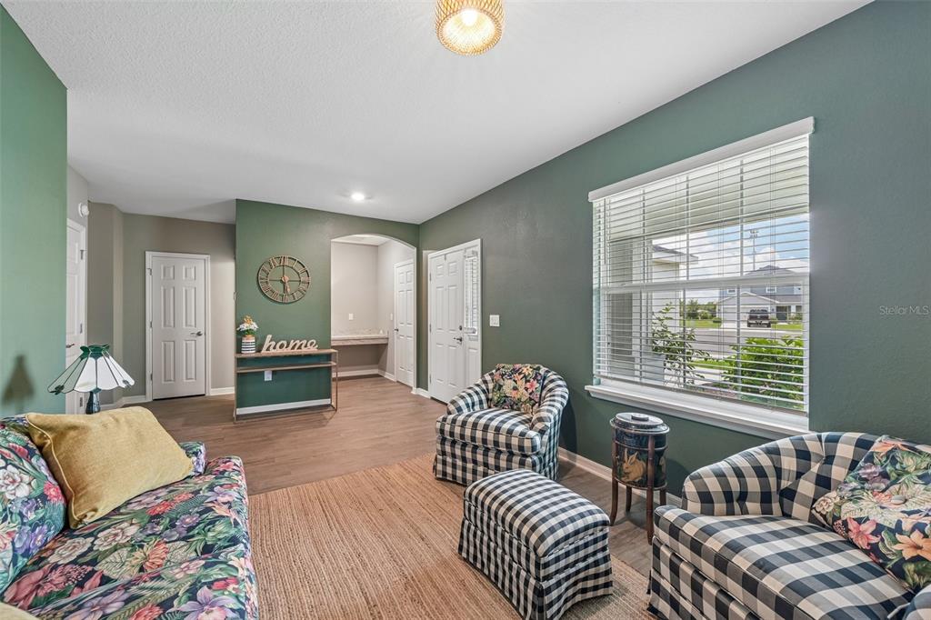 A living room features green walls, floral-patterned furniture, plaid armchairs, and a large window — 16113 67TH COURT E, PARRISH, FL