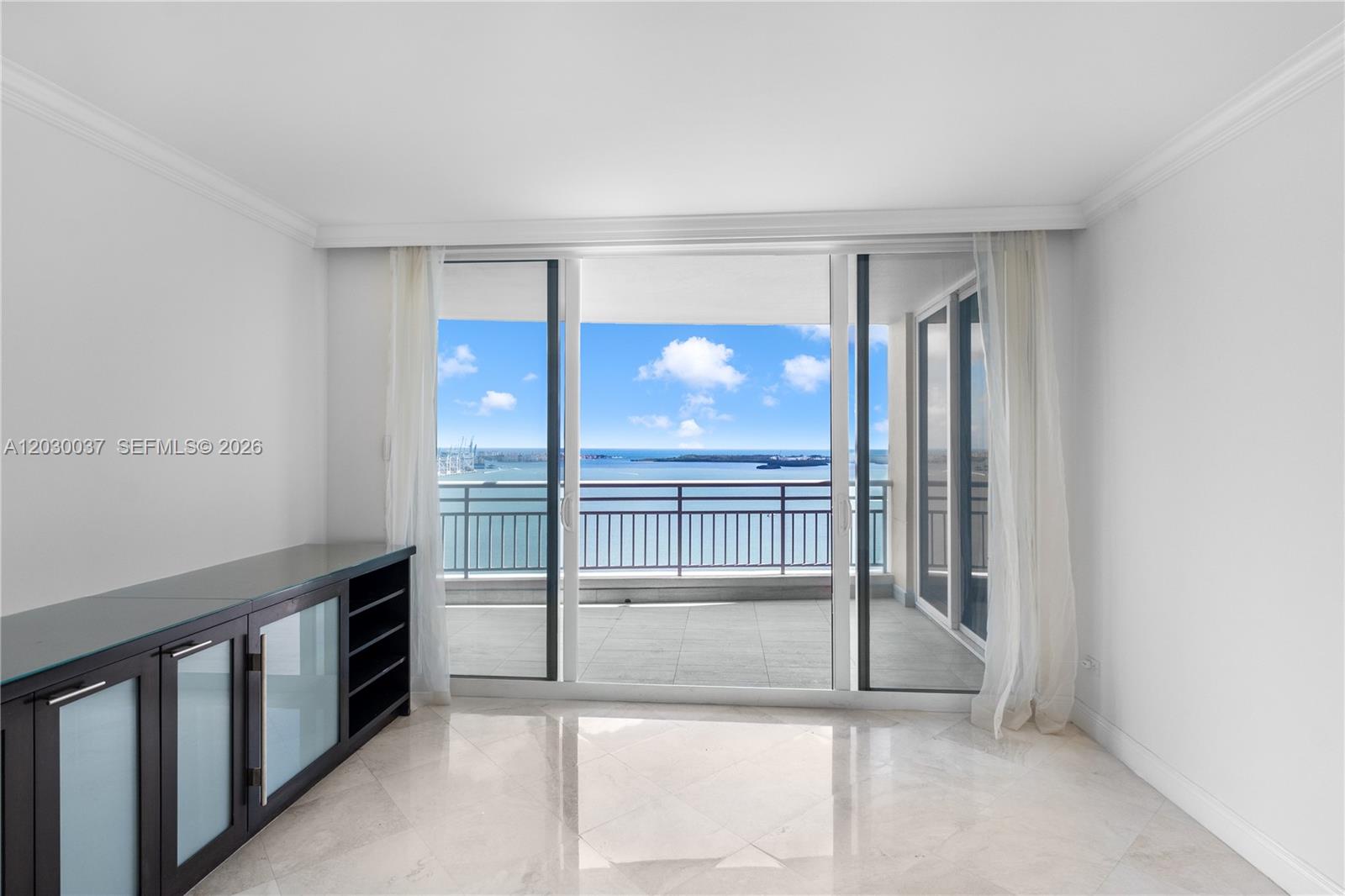A room with marble floors and a dark cabinet opens to a balcony overlooking water — 808 Brickell Key Dr # 3002, Miami FL 33131, MIAMI, FL