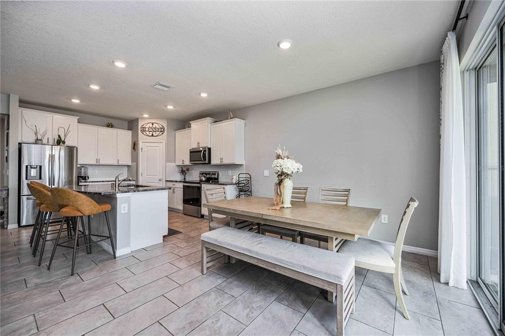 A kitchen and dining area featuring white cabinets, stainless steel appliances, and tile flooring — 5329 HALEWOOD COURT, BRADENTON, FL
