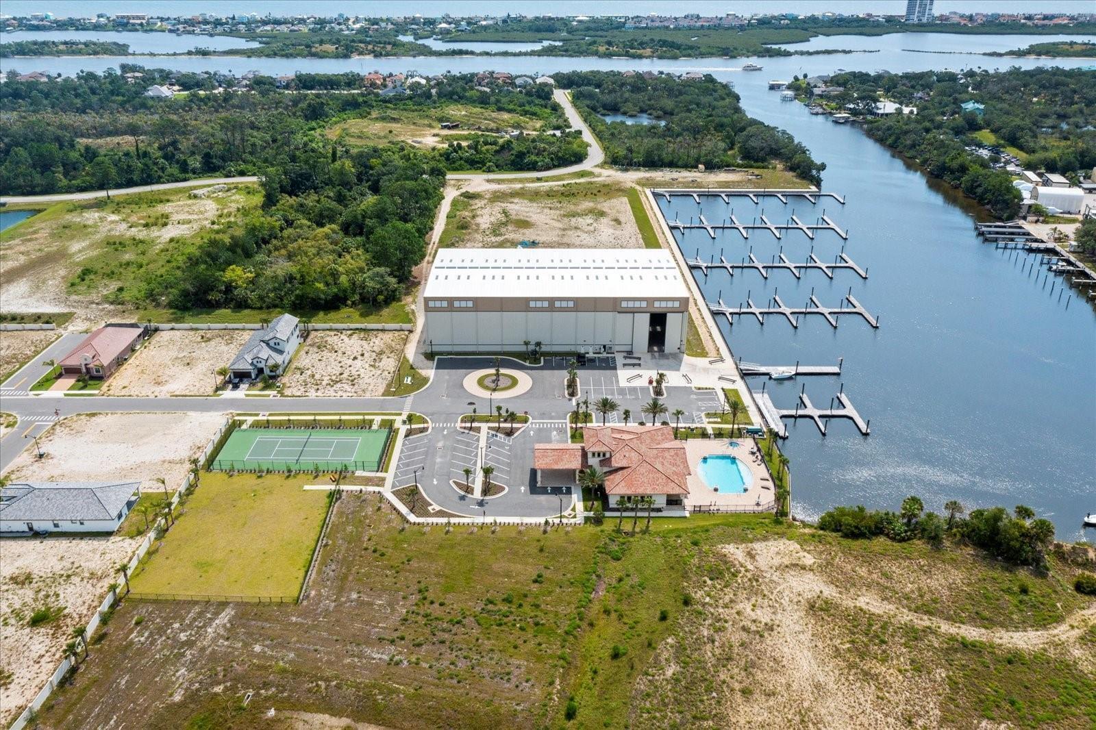 An aerial view of a large warehouse, a marina, a tennis court, and a pool — 27 Del Palma Drive, Palm Coast FL 32137, PALM COAST, FL