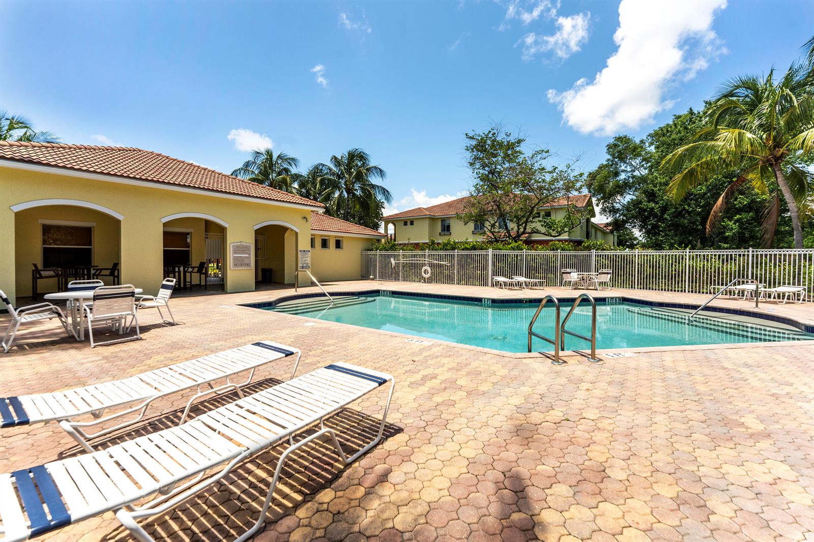 A swimming pool with lounge chairs on a paved patio next to a building — 49 SE Sedona Circle # 101, Stuart FL 34994, STUART, FL