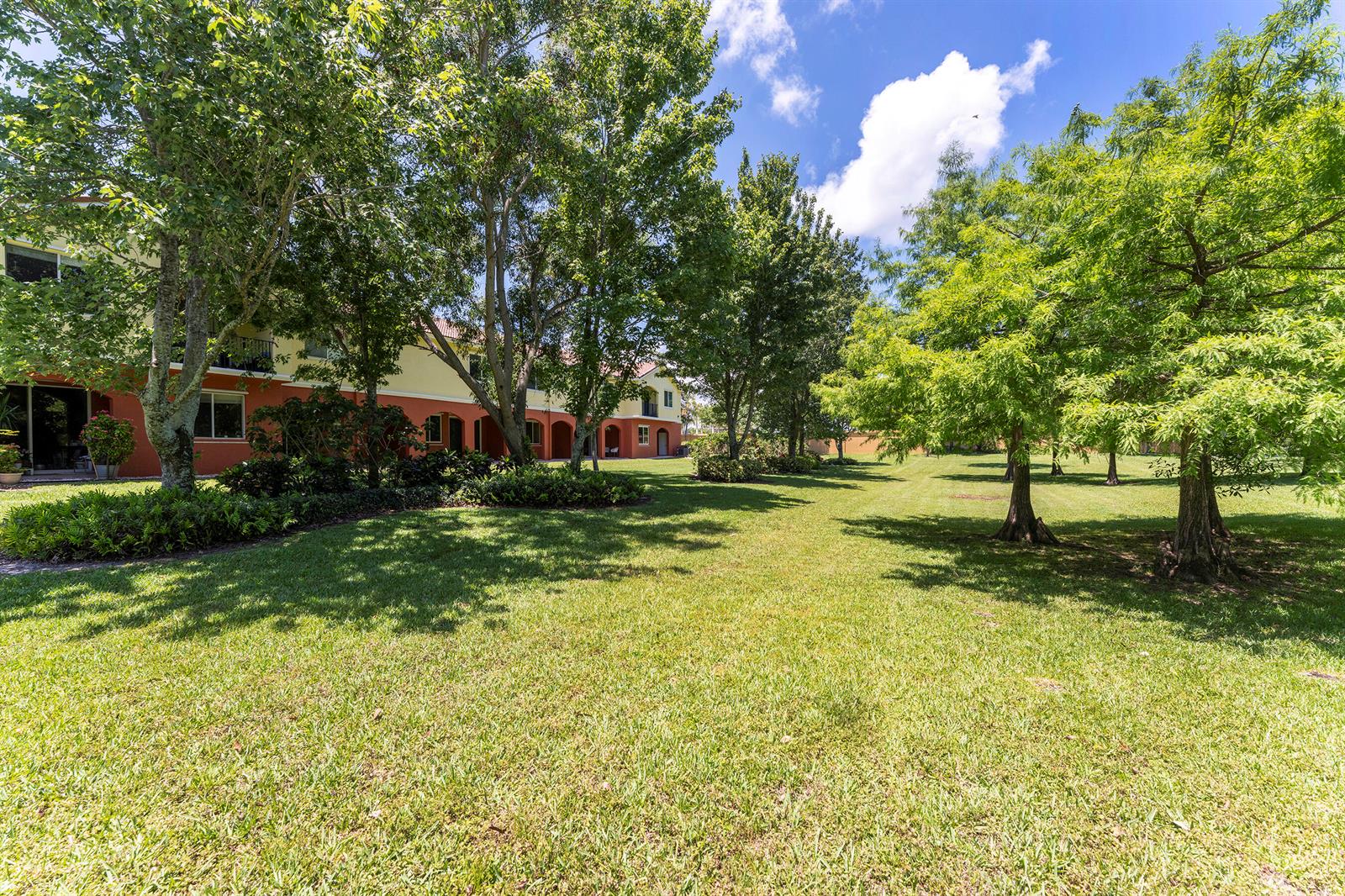A multi-story apartment building with a red and yellow exterior sits beside a grassy lawn — 49 SE Sedona Circle # 101, Stuart FL 34994, STUART, FL