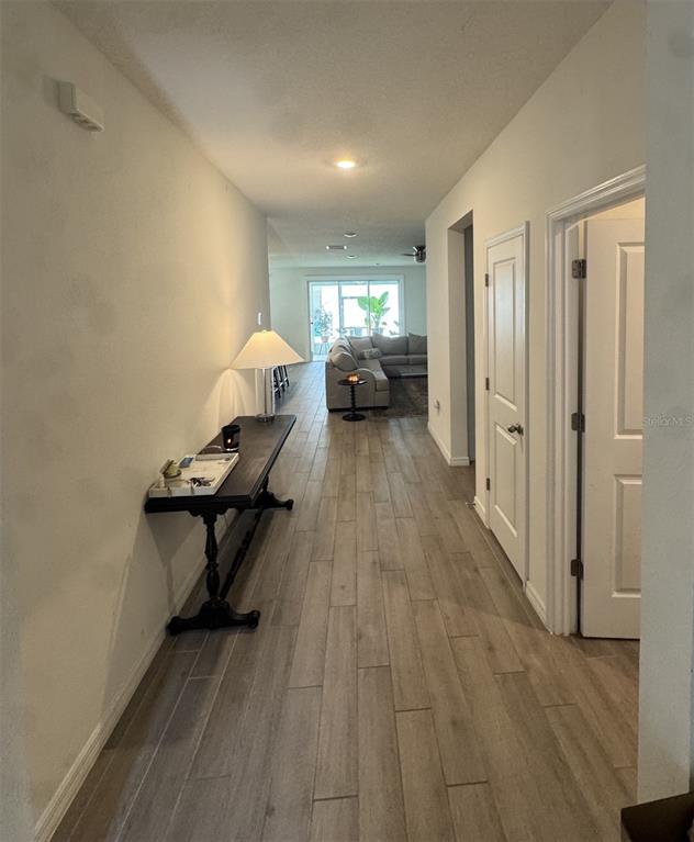 A hallway with wood-look tile flooring leads to a living room with a sectional sofa — 1287 NW 136TH STREET, NEWBERRY, FL