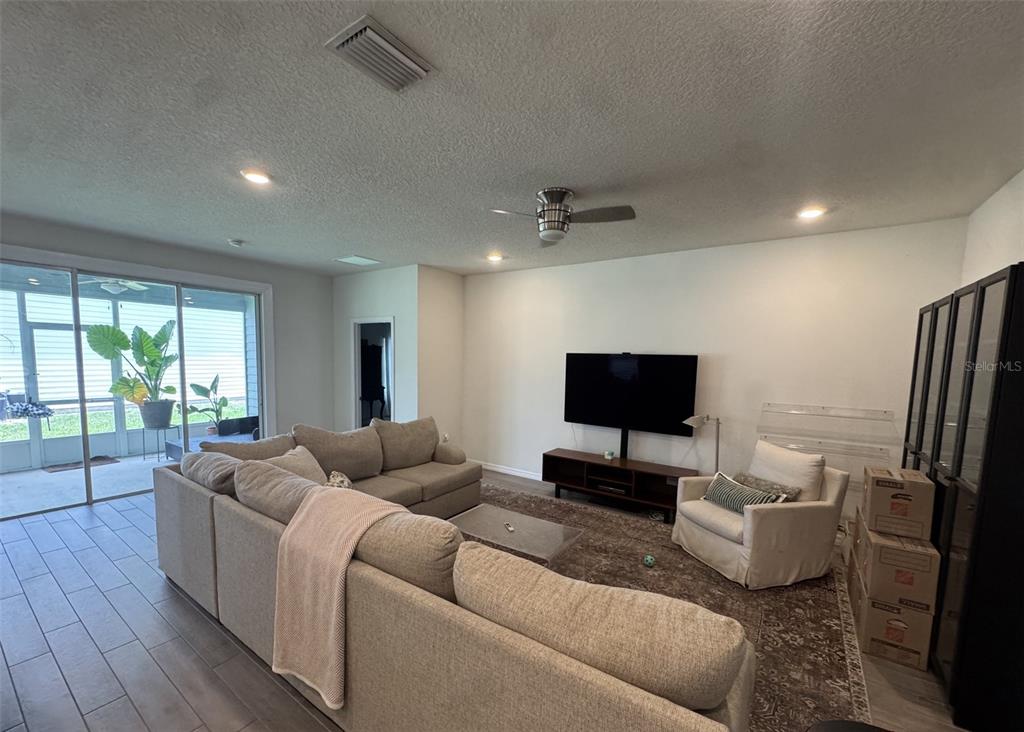 A living room features a large sectional sofa, a television on a stand, and sliding doors — 1287 NW 136TH STREET, NEWBERRY, FL
