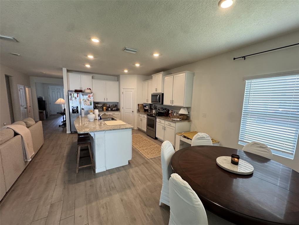 A kitchen with white cabinets, granite countertops, and an island opens to a dining area — 1287 NW 136TH STREET, NEWBERRY, FL