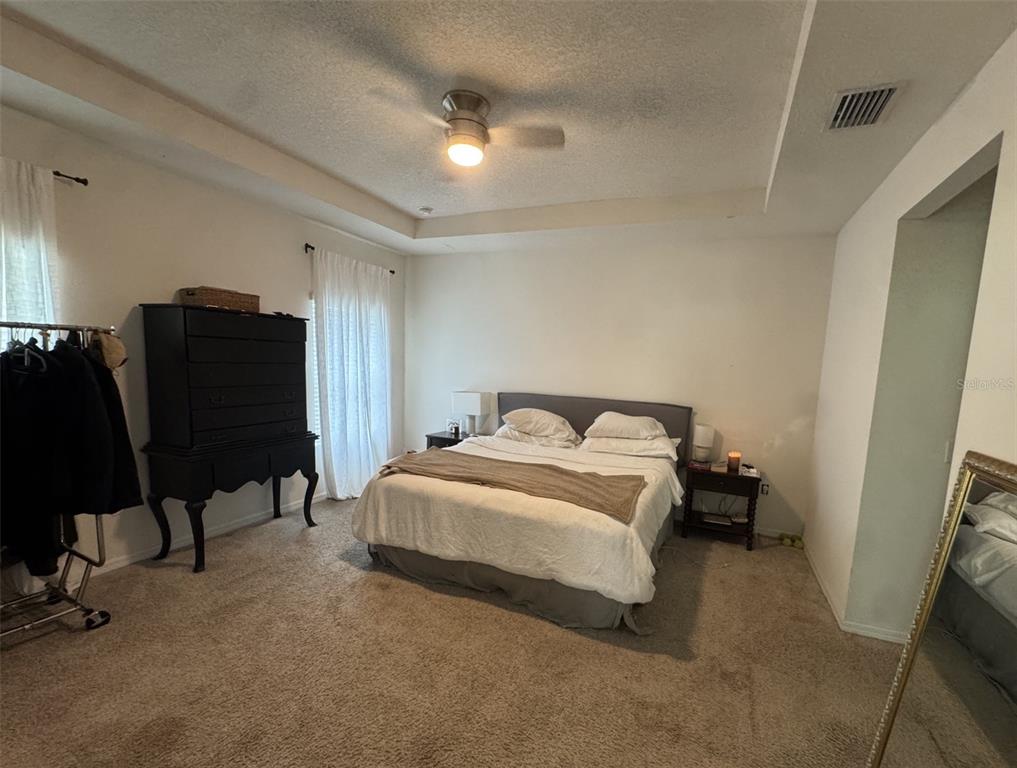 A bedroom features a bed, a tall black dresser, a clothing rack, and carpeted floors — 1287 NW 136TH STREET, NEWBERRY, FL