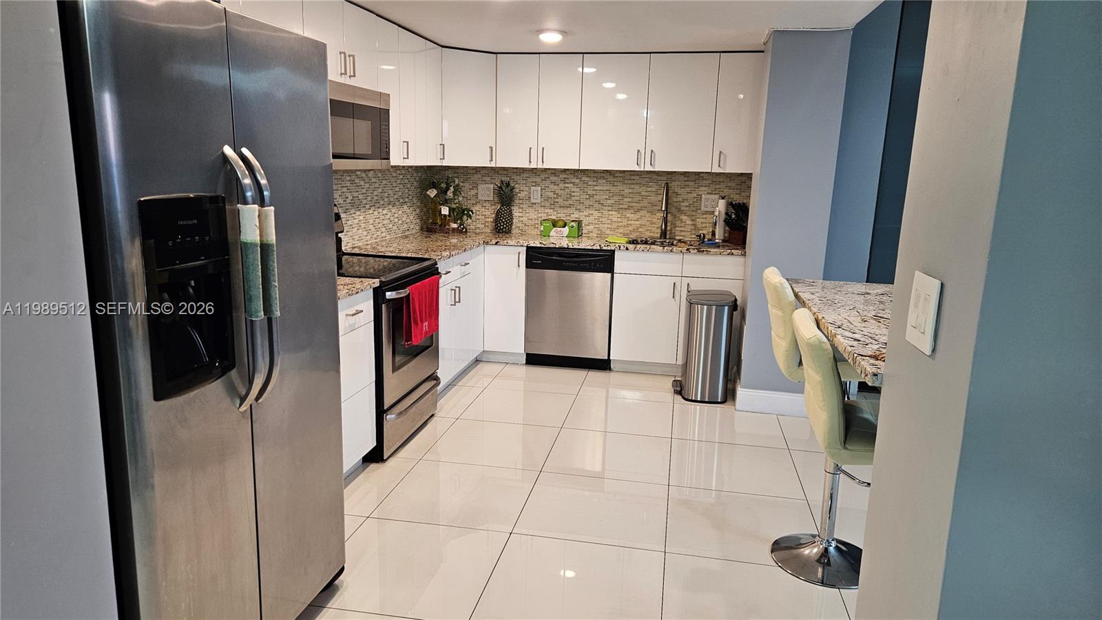 A modern kitchen features white cabinets, stainless steel appliances, and light-colored tile flooring — 11111 Biscayne Blvd # 3F, Miami FL 33181, MIAMI, FL