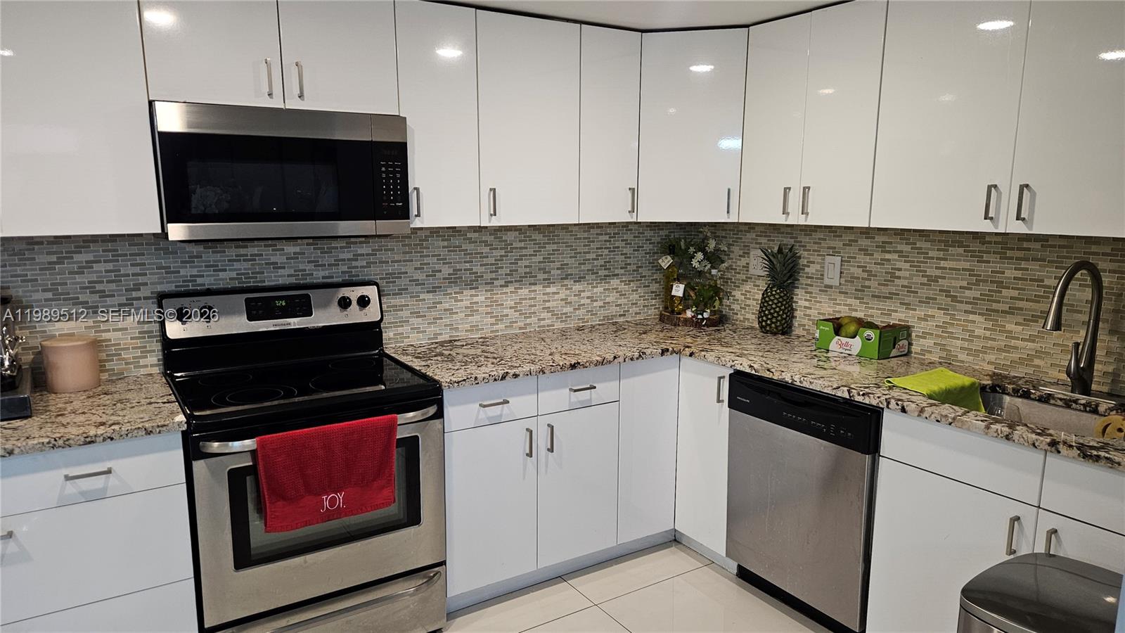 A kitchen features white cabinets, granite countertops, stainless steel appliances, and a tiled backsplash — 11111 Biscayne Blvd # 3F, Miami FL 33181, MIAMI, FL