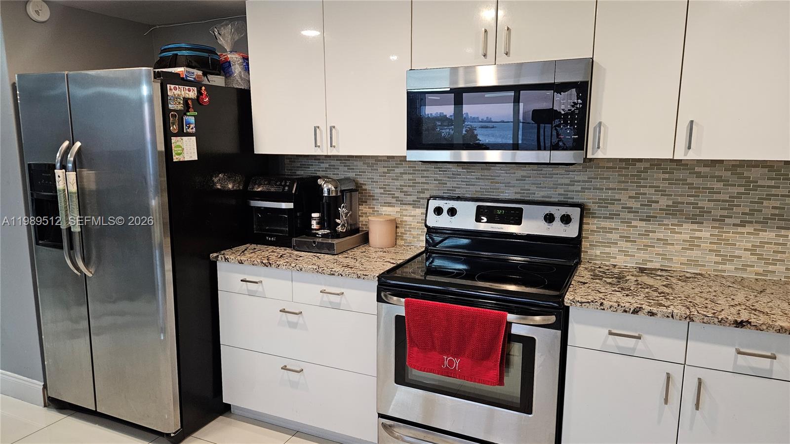A kitchen features white cabinets, stainless steel appliances, granite countertops, and a tiled backsplash — 11111 Biscayne Blvd # 3F, Miami FL 33181, MIAMI, FL