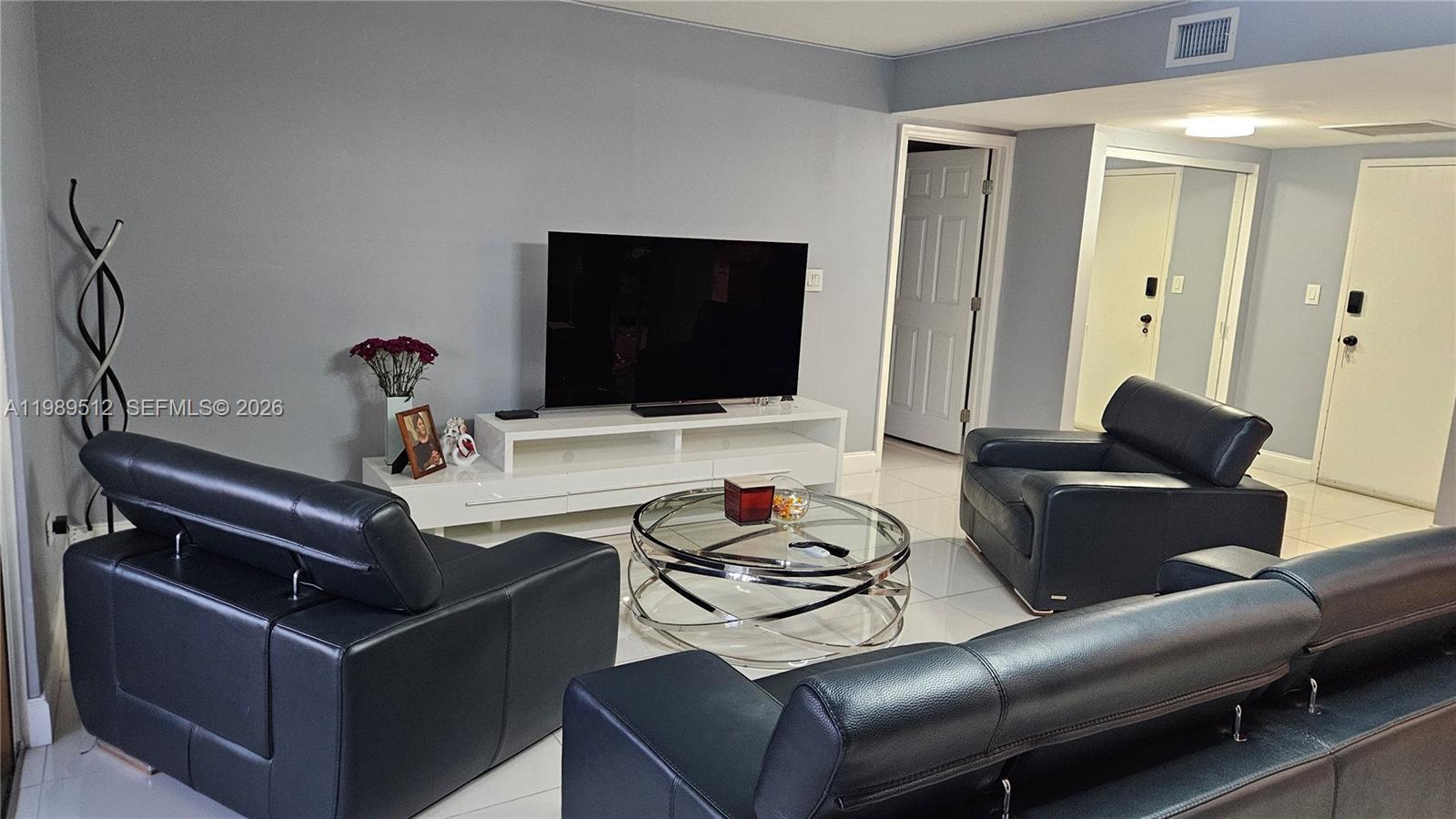 A living room features black leather furniture, a glass coffee table, and a white media console — 11111 Biscayne Blvd # 3F, Miami FL 33181, MIAMI, FL