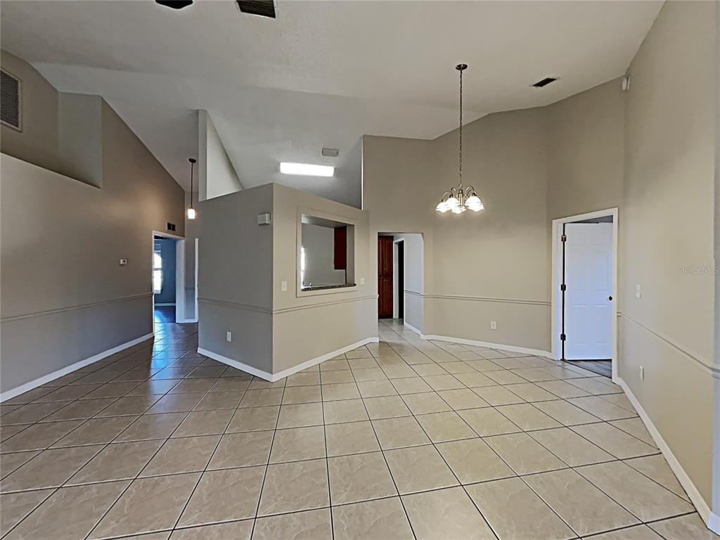An open-concept dining area features vaulted ceilings, tile flooring, and a pass-through window to the kitchen — 11701 LYNMOOR DRIVE, RIVERVIEW, FL
