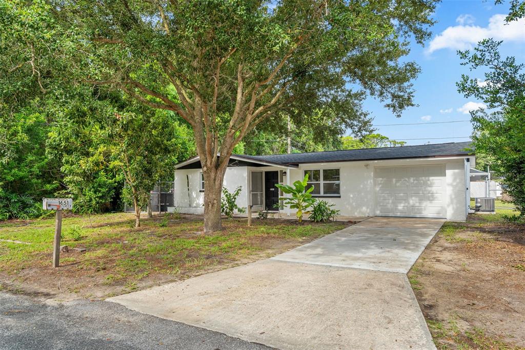 A single-story white house with a garage and a large tree in the front yard — 1651 ATLAS LANE, HOLIDAY, FL