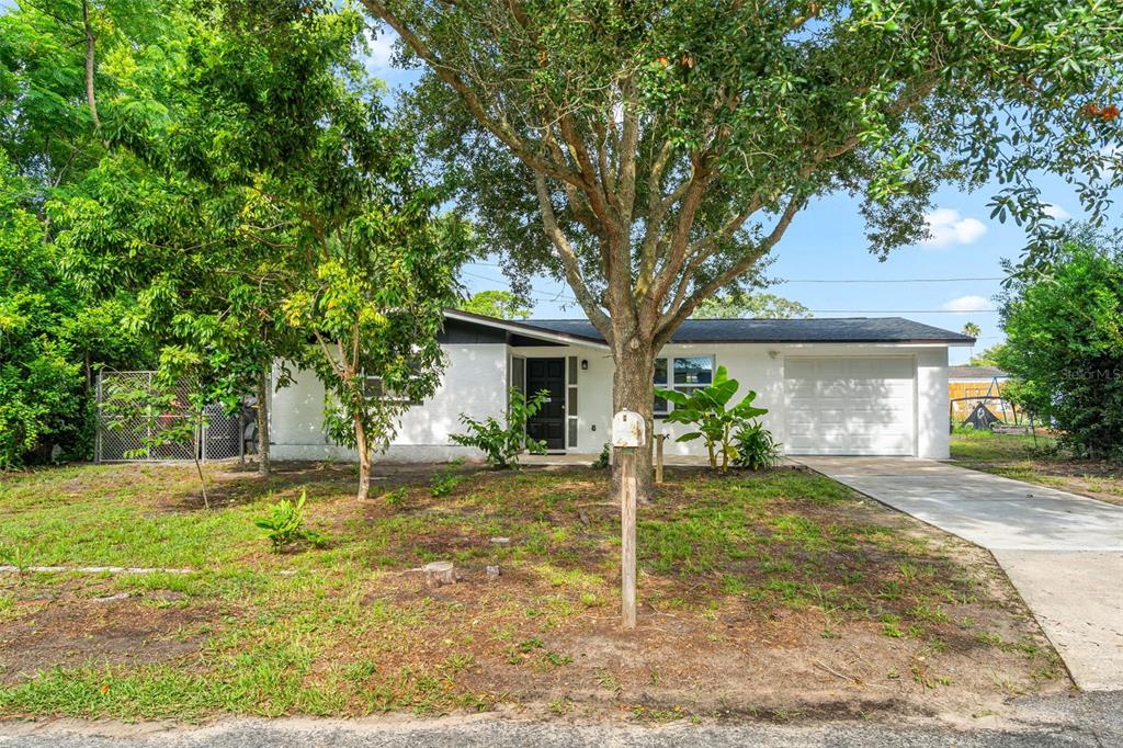 A single-story white house with a garage and a large tree in the front yard — 1651 ATLAS LANE, HOLIDAY, FL