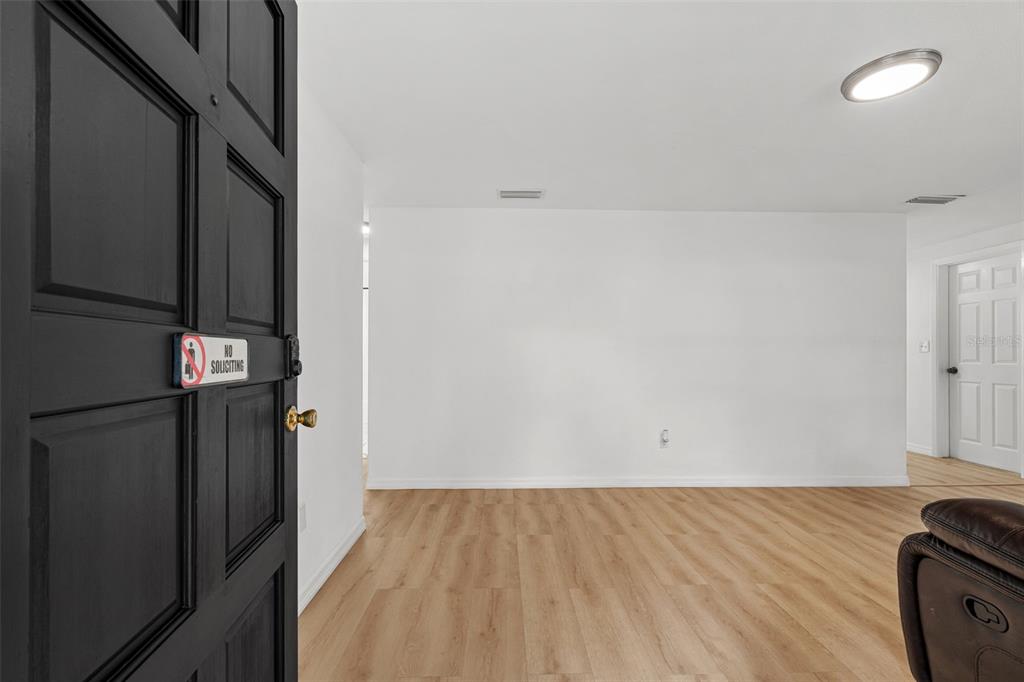 A view from an open black door into a room with white walls and flooring — 1651 ATLAS LANE, HOLIDAY, FL