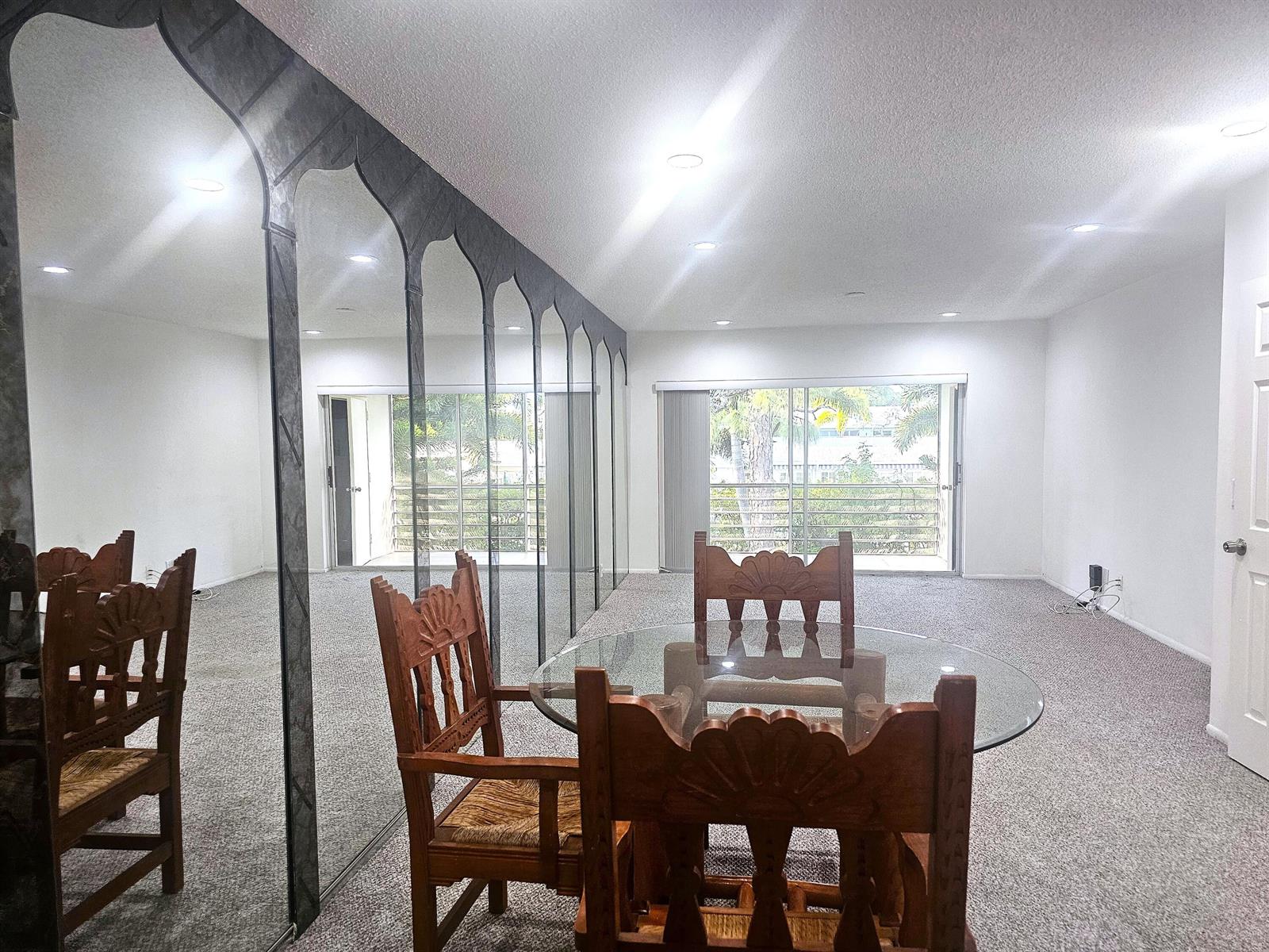 A dining area features a glass-topped table, wooden chairs, and a large decorative mirrored wall — 2600 SW 22nd Avenue # 908, Delray Beach FL 33445, DELRAY BEACH, FL