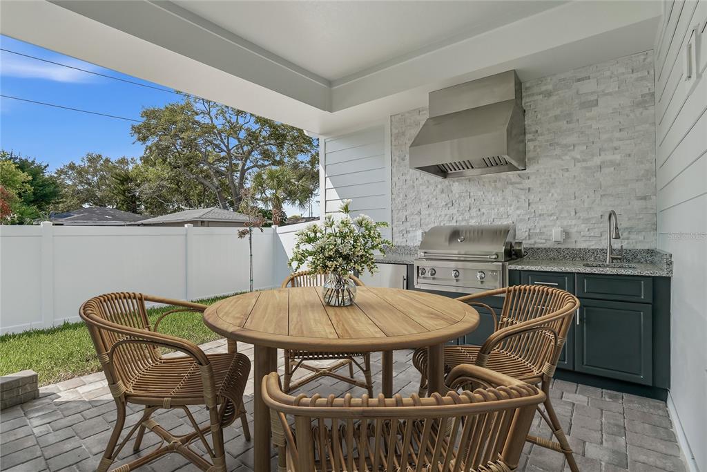 A covered outdoor patio features a dining set, a built-in grill, and a sink — 879 53RD AVENUE N, ST PETERSBURG, FL