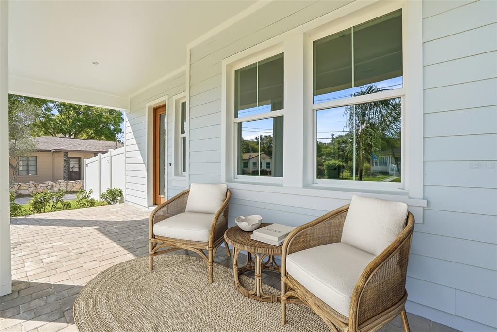A covered front porch features light blue siding, two wicker chairs, and a small table — 879 53RD AVENUE N, ST PETERSBURG, FL