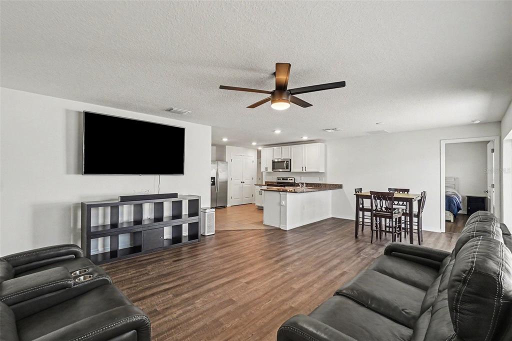 An open-concept living room and kitchen area with dark wood flooring and leather furniture — 10213 CLOUDBURST COURT, RIVERVIEW, FL