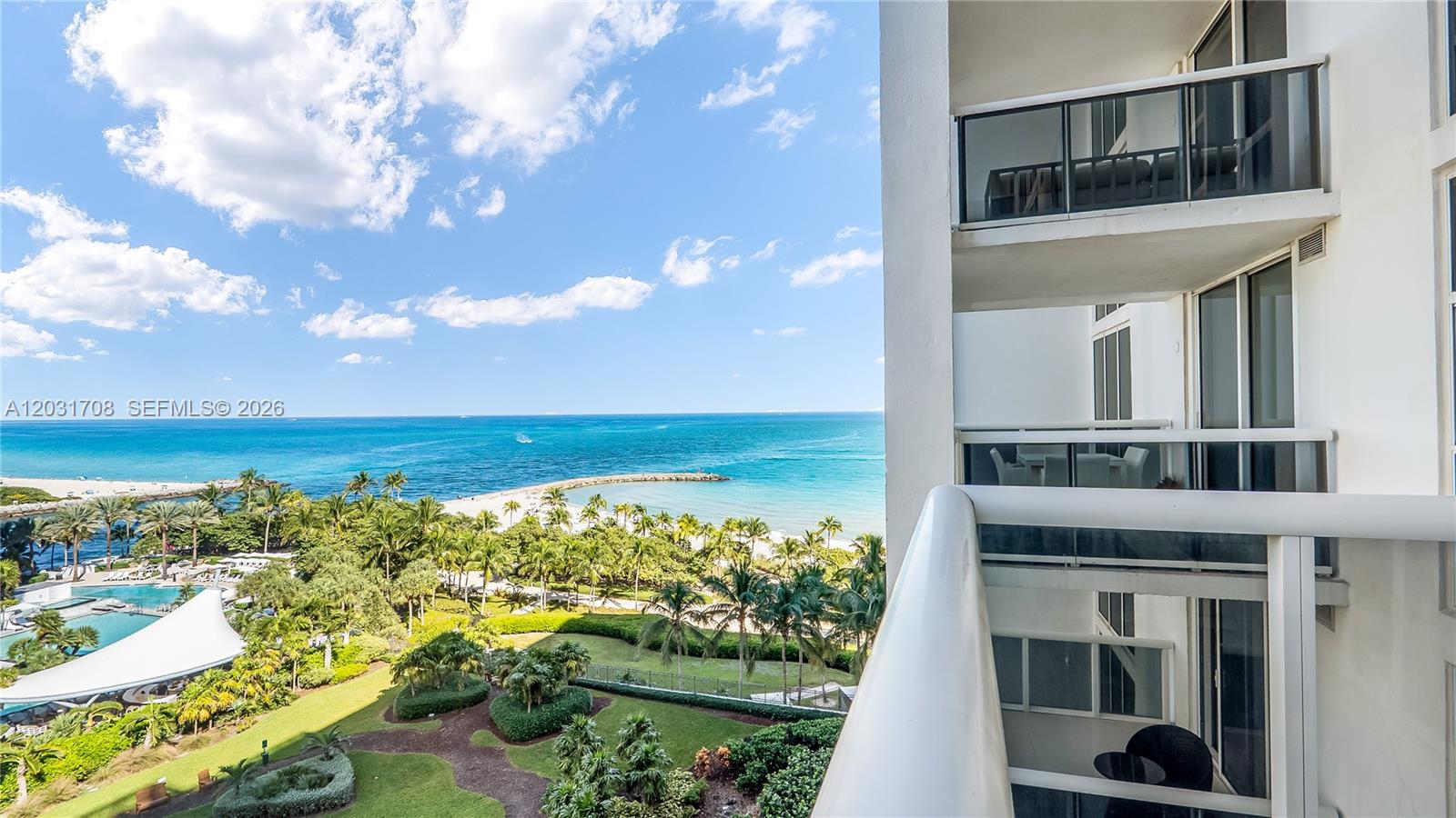 A high-angle view from a balcony overlooks a tropical beach, ocean, and landscaped grounds — 10275 Collins Ave # 905, Bal Harbour FL 33154, BAL HARBOUR, FL