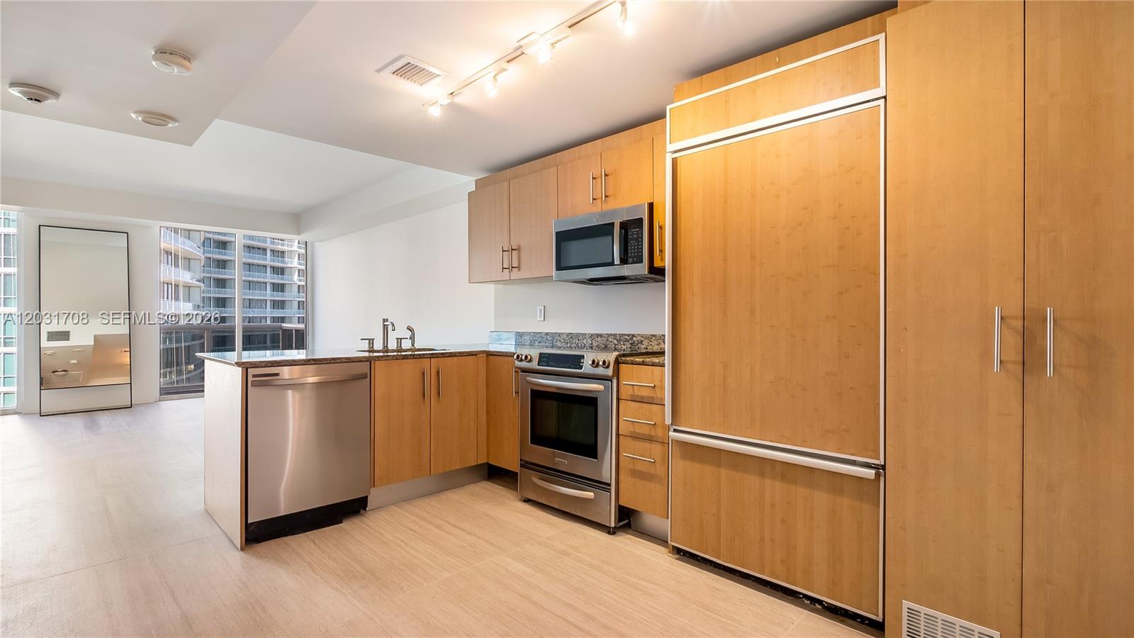 A kitchen features light wood cabinetry, stainless steel appliances, and a granite countertop — 10275 Collins Ave # 905, Bal Harbour FL 33154, BAL HARBOUR, FL