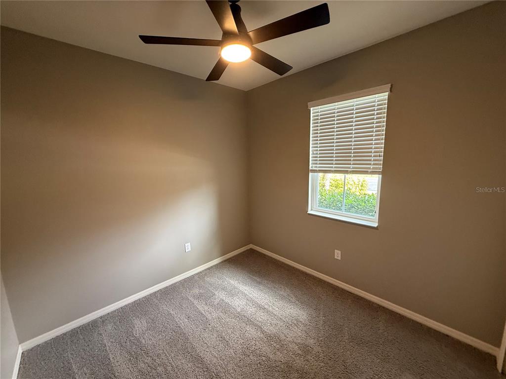 An empty bedroom features gray walls, carpeted flooring, a ceiling fan, and a window with blinds — 2049 MESIC HAMMOCK WAY, VENICE, FL