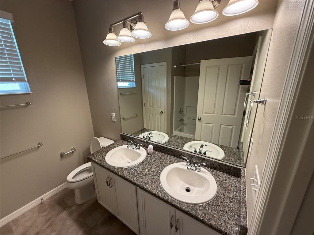 A bathroom features a double vanity with a granite countertop and a large wall mirror — 2049 MESIC HAMMOCK WAY, VENICE, FL