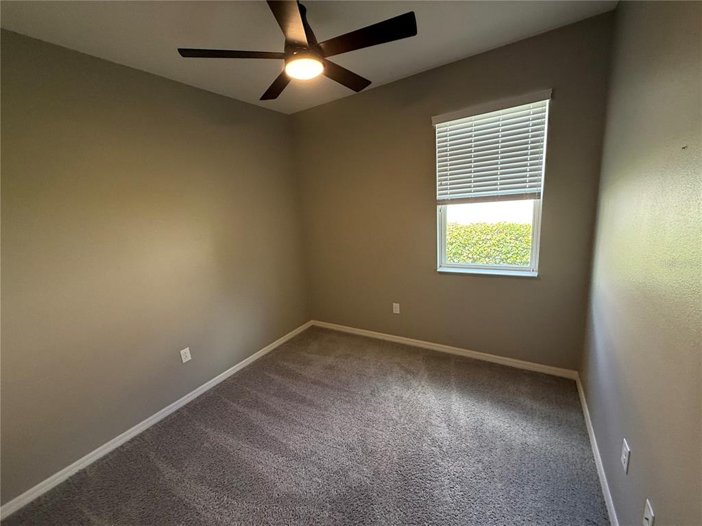 An empty bedroom features gray walls, gray carpeting, a ceiling fan, and a window — 2049 MESIC HAMMOCK WAY, VENICE, FL
