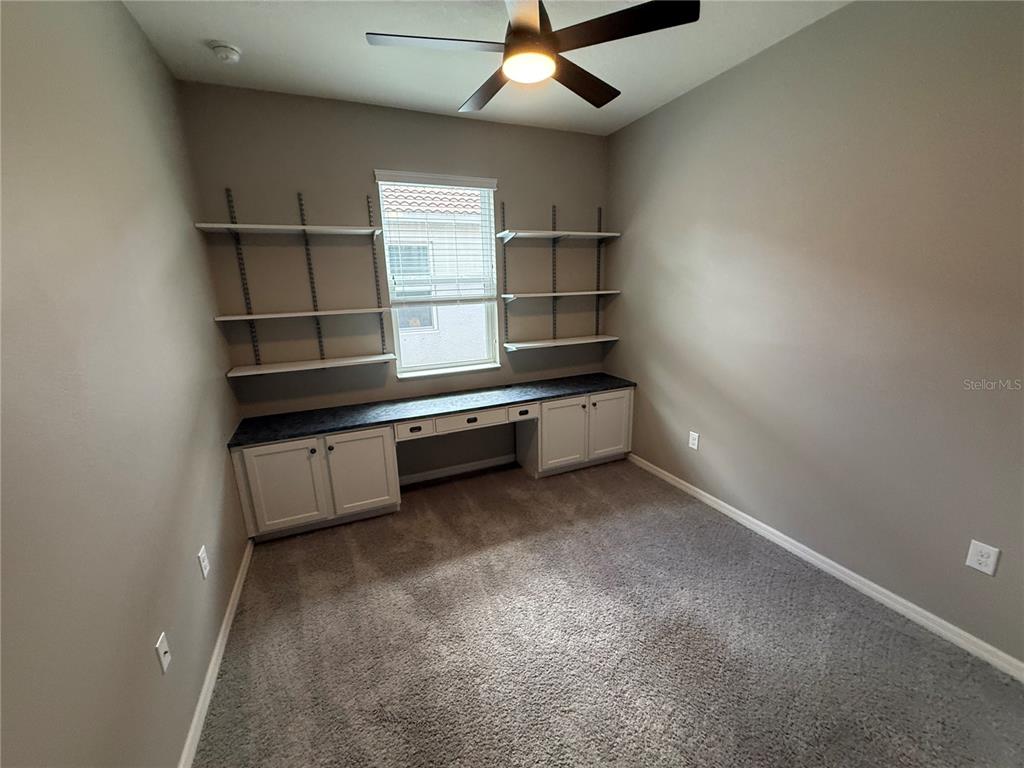 A home office features built-in cabinetry, shelving, a ceiling fan, and wall-to-wall carpeting — 2049 MESIC HAMMOCK WAY, VENICE, FL