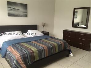 A bedroom features a bed with a striped blanket, a dark dresser, and a wall mirror — 250 S Shore Dr # 5, Miami Beach FL 33141, MIAMI BEACH, FL