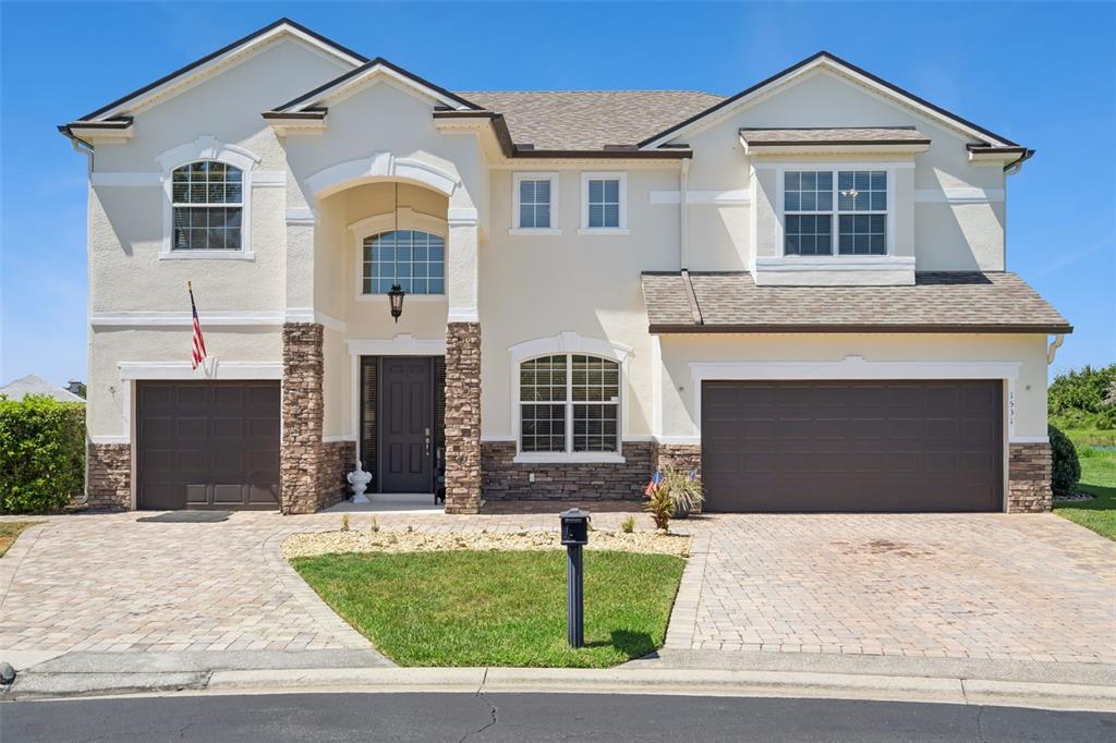 A two-story house with a beige stucco facade, stone accents, and two garage doors — 1531 LEXINGTON AVENUE, DAVENPORT, FL