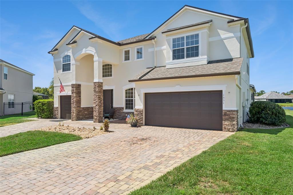 A two-story house features a stone-accented facade, a paved driveway, and a three-car garage — 1531 LEXINGTON AVENUE, DAVENPORT, FL