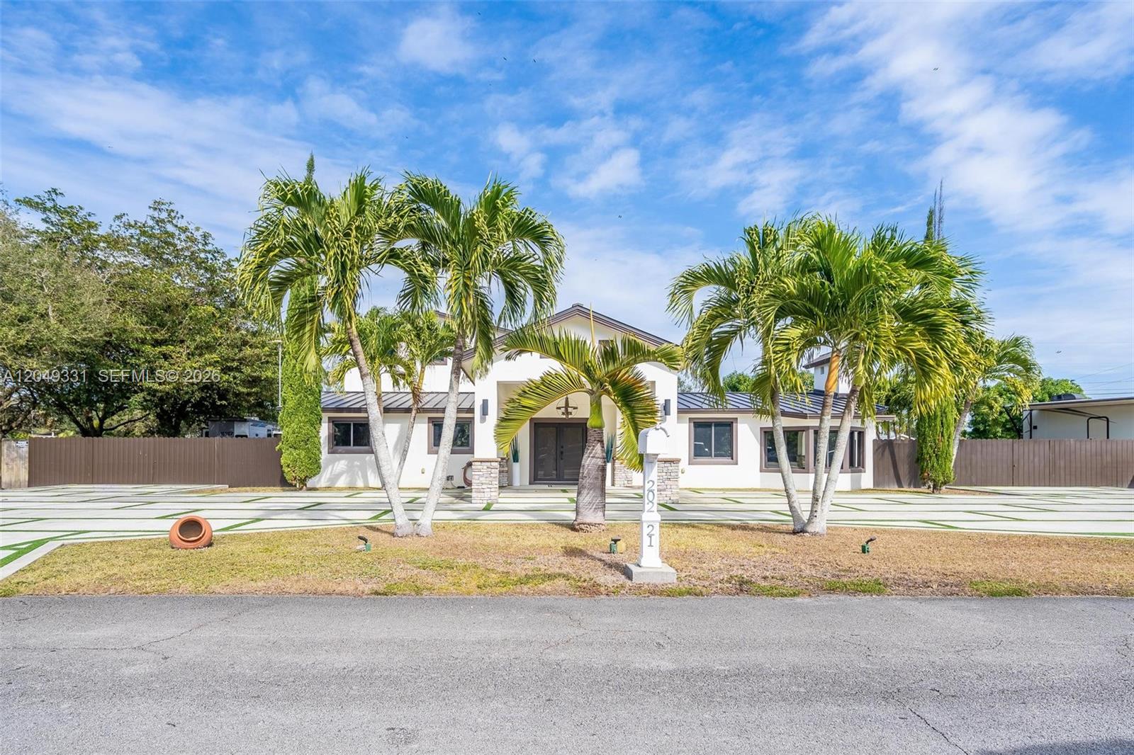 A single-story house with a white exterior, palm trees, and a large paved driveway — 20221 SW 318th St, Homestead FL 33030, HOMESTEAD, FL