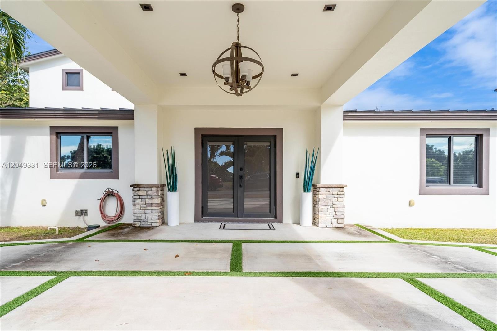 The front entrance features a covered porch with a hanging chandelier and double glass doors — 20221 SW 318th St, Homestead FL 33030, HOMESTEAD, FL