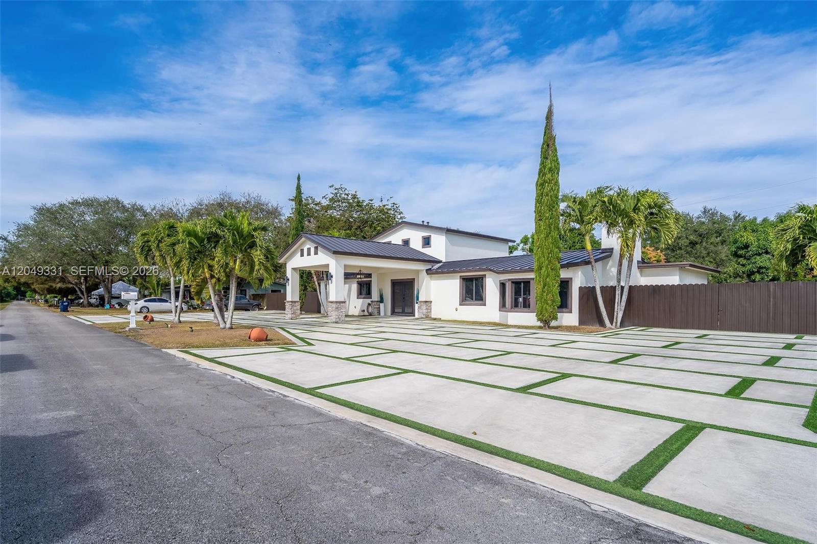 A white house with a metal roof features a large concrete driveway with grass strips — 20221 SW 318th St, Homestead FL 33030, HOMESTEAD, FL