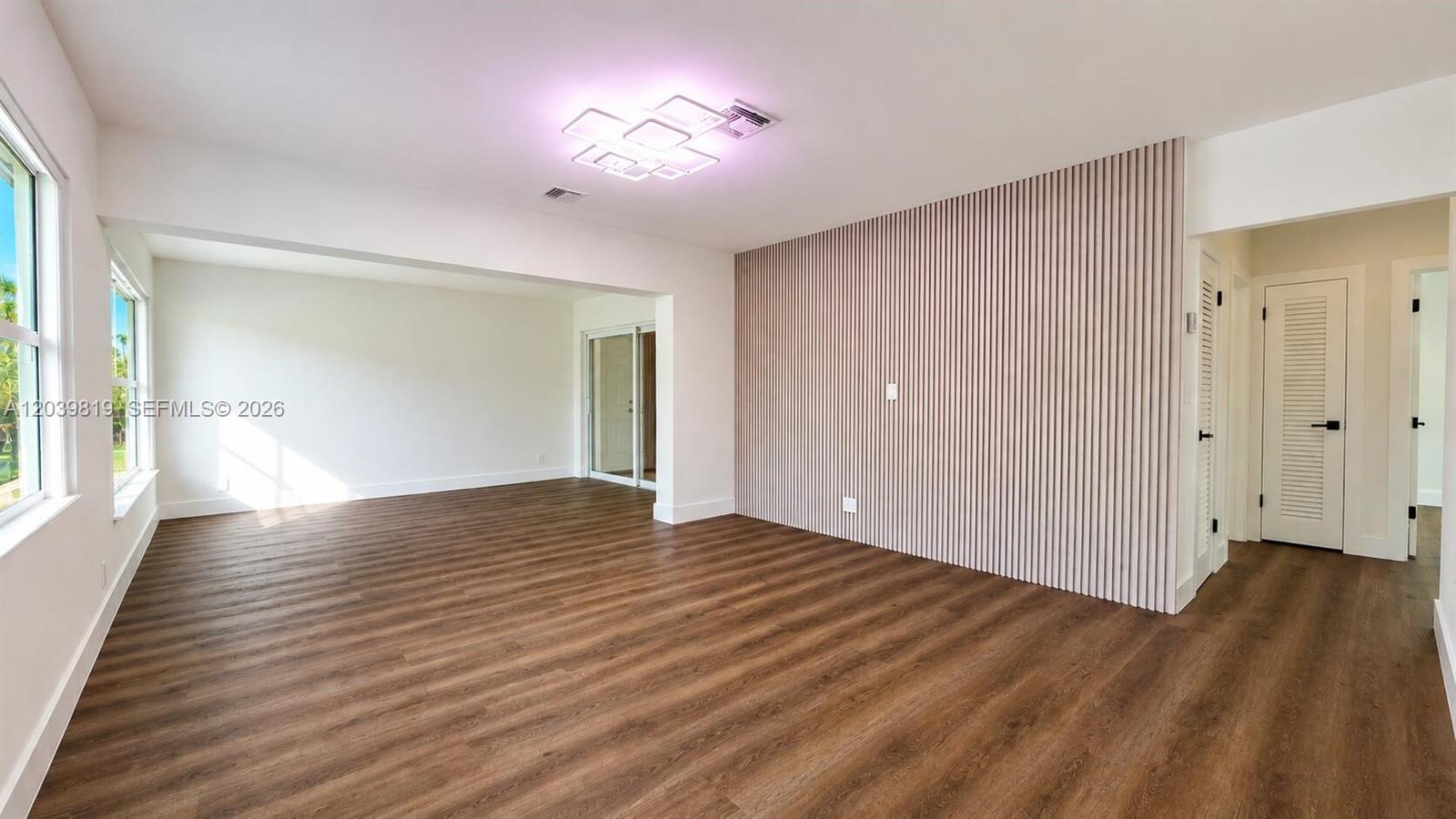 A living room features wood-look flooring, a slatted accent wall, and a modern ceiling light — 1155 Hayes St, Hollywood FL 33019, HOLLYWOOD, FL