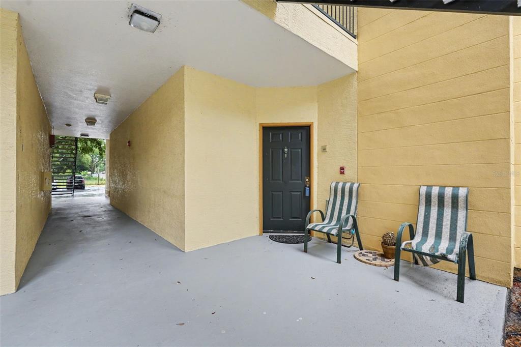 A covered patio with two striped chairs sits outside a dark front door — 5602 PINNACLE HEIGHTS CIRCLE UNIT 108, TAMPA, FL