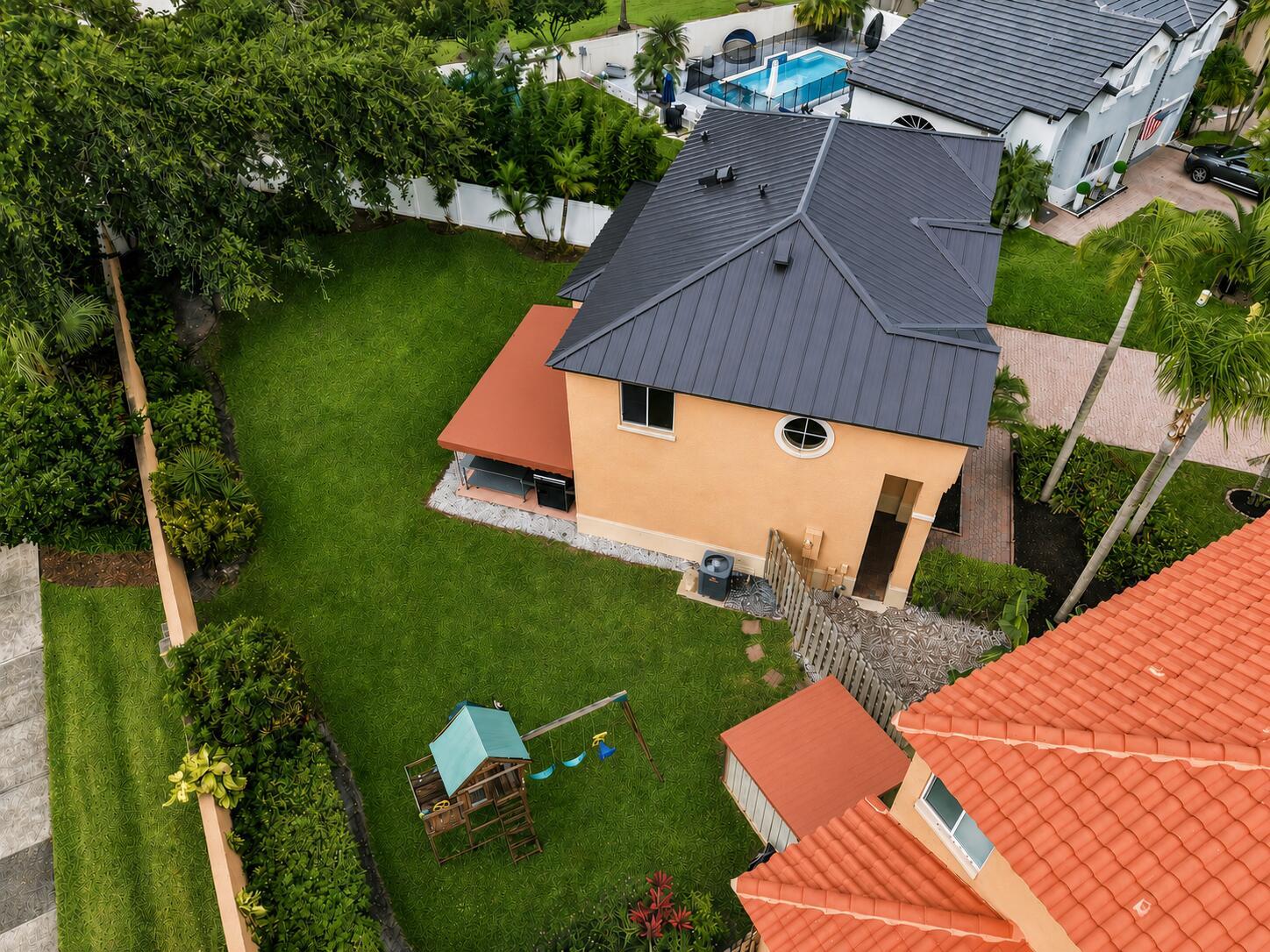 An aerial view shows a two-story house with a dark metal roof and backyard — 2510 Rampart Way S, Hollywood FL 33026, HOLLYWOOD, FL