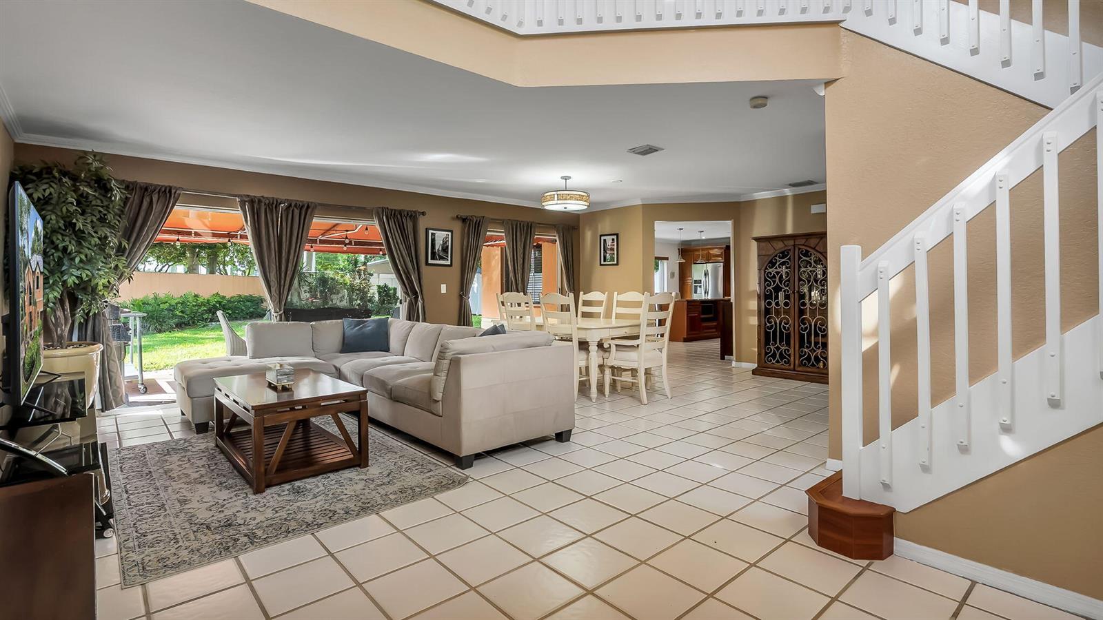A living room with tile floors, a sectional sofa, and a staircase leads to a dining area — 2510 Rampart Way S, Hollywood FL 33026, HOLLYWOOD, FL