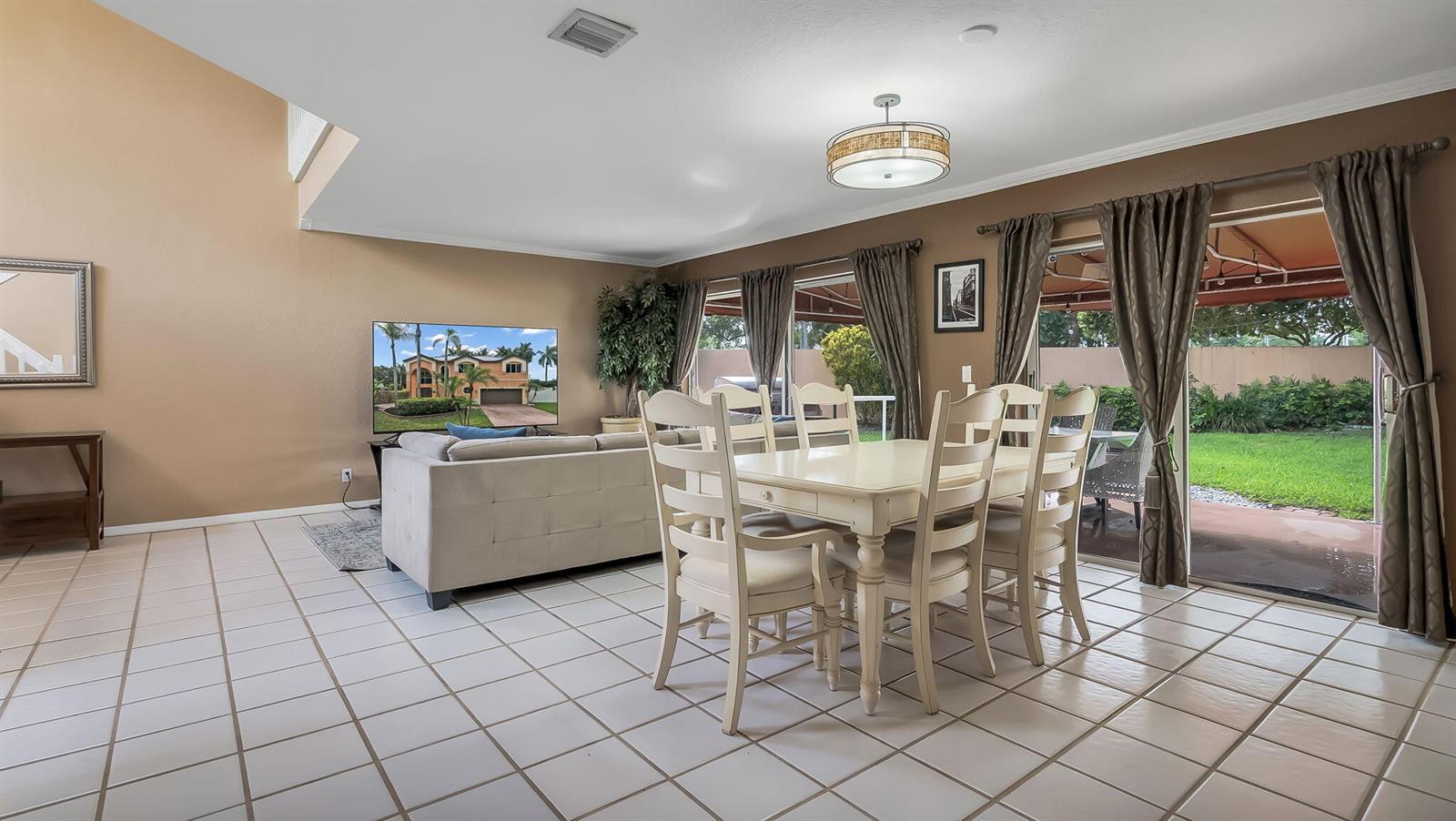 A living and dining area with tile floors, a beige sofa, and sliding glass doors — 2510 Rampart Way S, Hollywood FL 33026, HOLLYWOOD, FL