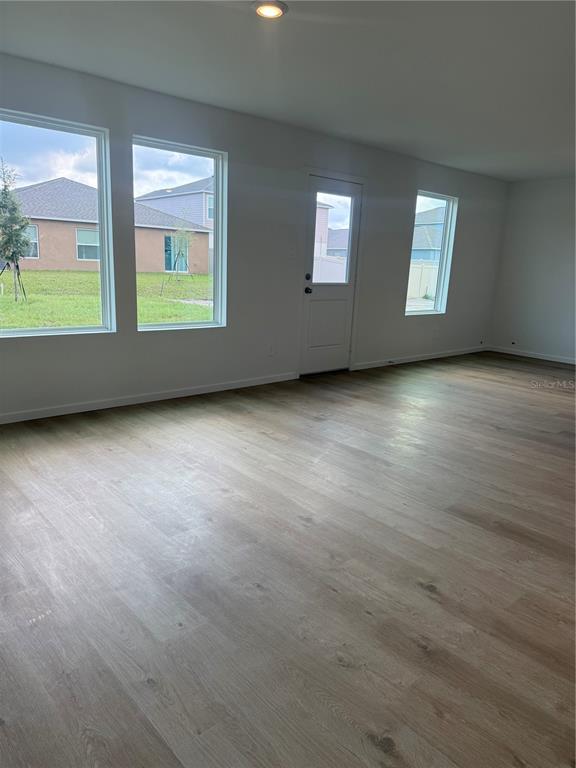 An empty room features light wood-look flooring, white walls, large windows, and a glass-paneled door — 3463 ROVER ROAD, EAGLE LAKE, FL