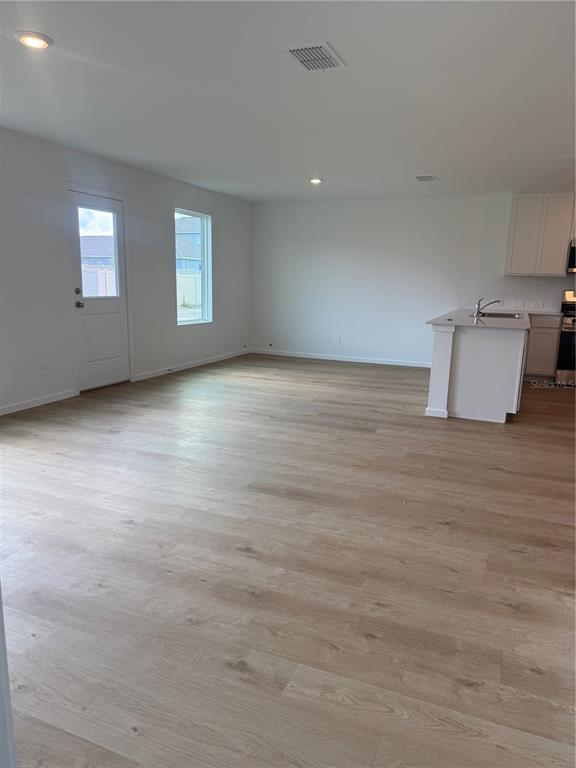 An open-concept room features light wood-look flooring, white walls, a glass-paneled door, and a kitchen island — 3463 ROVER ROAD, EAGLE LAKE, FL