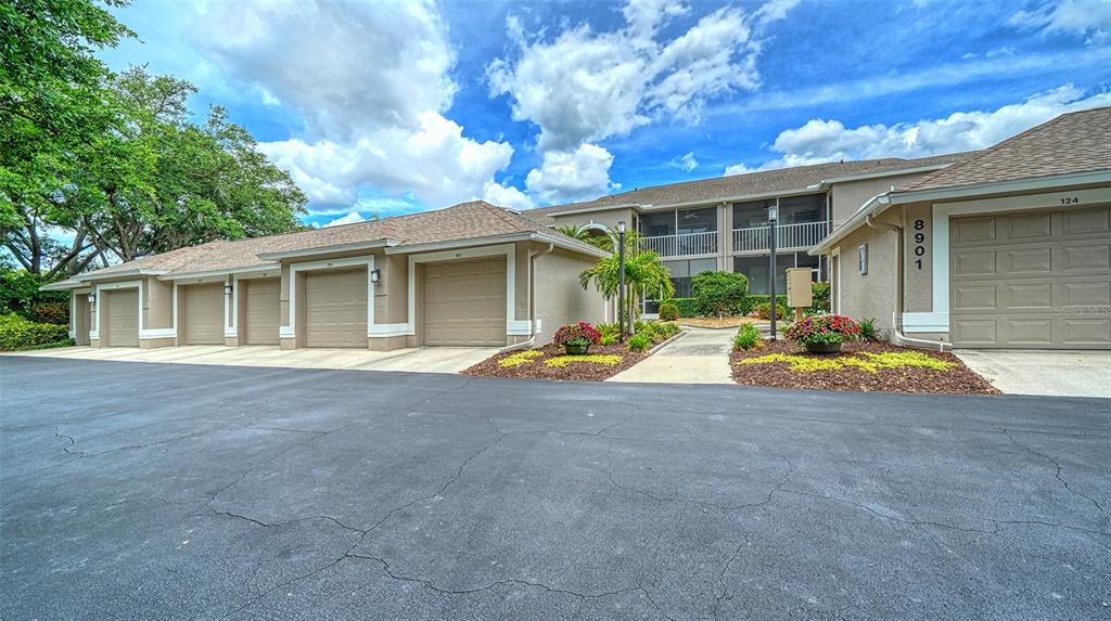 An exterior view of a residential building featuring a row of garages and a walkway — 8901 VERANDA WAY UNIT 111, SARASOTA, FL